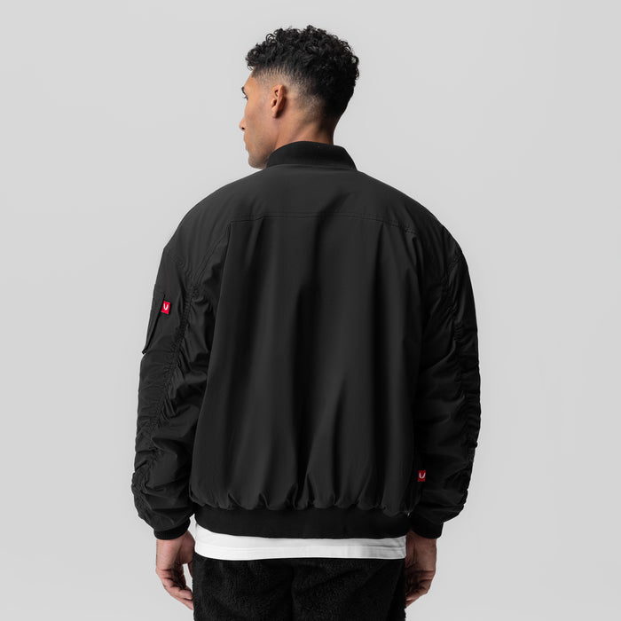 Black sherpa-lined insulated bomber jacket worn by model, back view