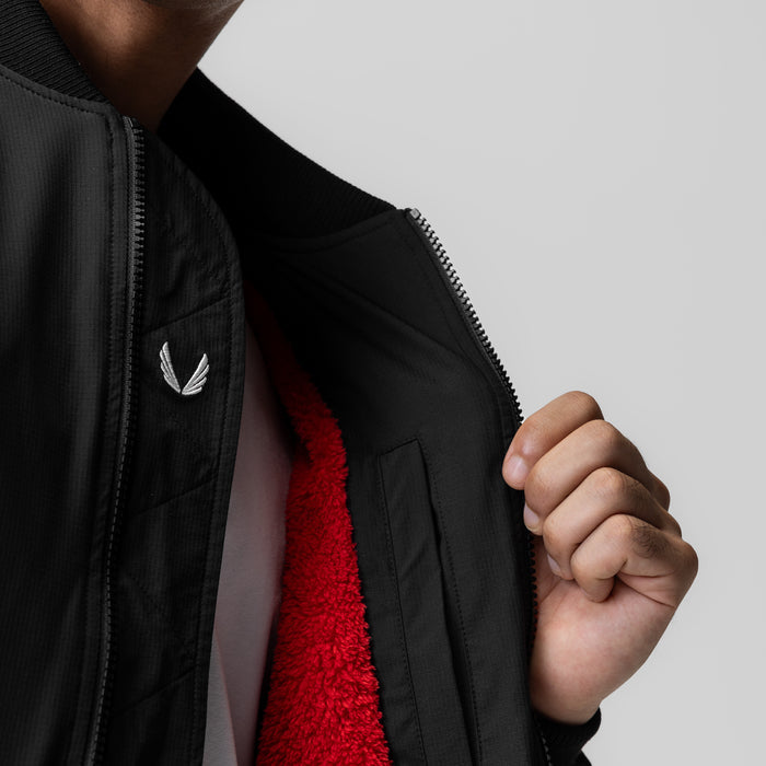 Black sherpa-lined insulated bomber jacket worn open, revealing red fleece lining, front view