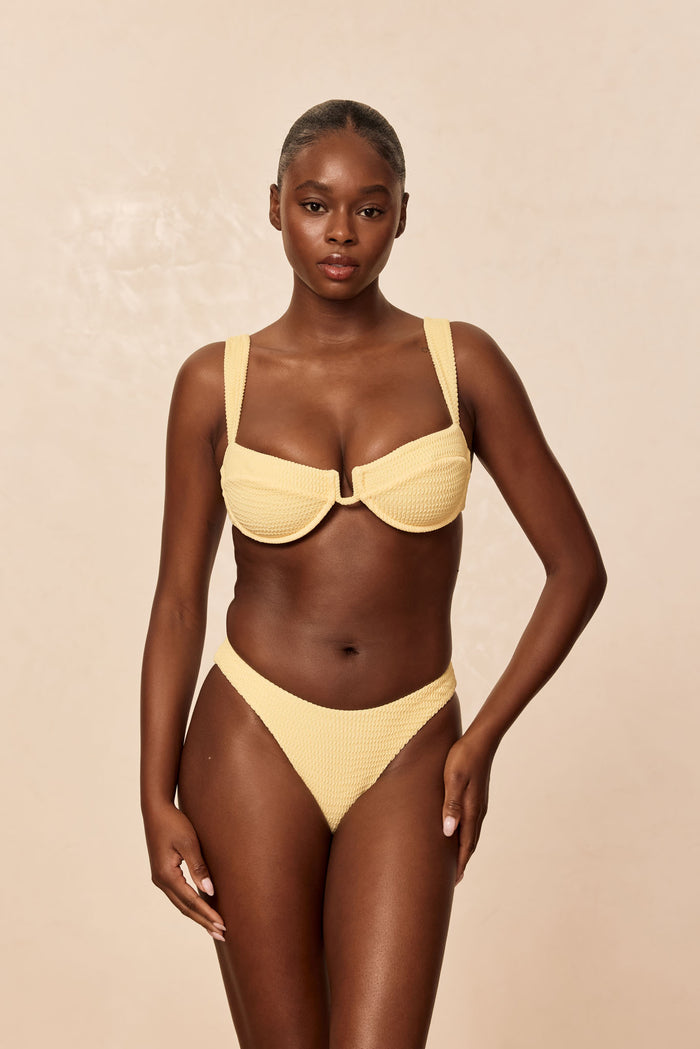 Front view of Byron Bottom in Honey Crinkle with high-leg V-cut and textured fabric on model against beige background