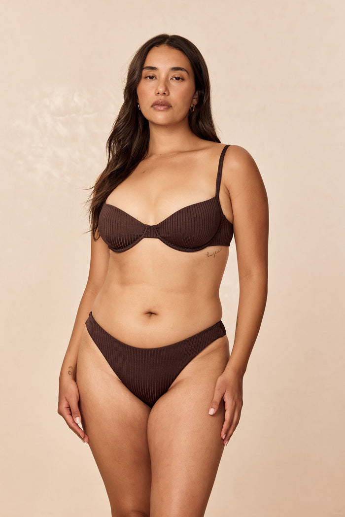 Front view of Capri Top in Espresso Wide Rib on model showing enhanced underwire cups, adjustable straps, and ribbed texture on beige background