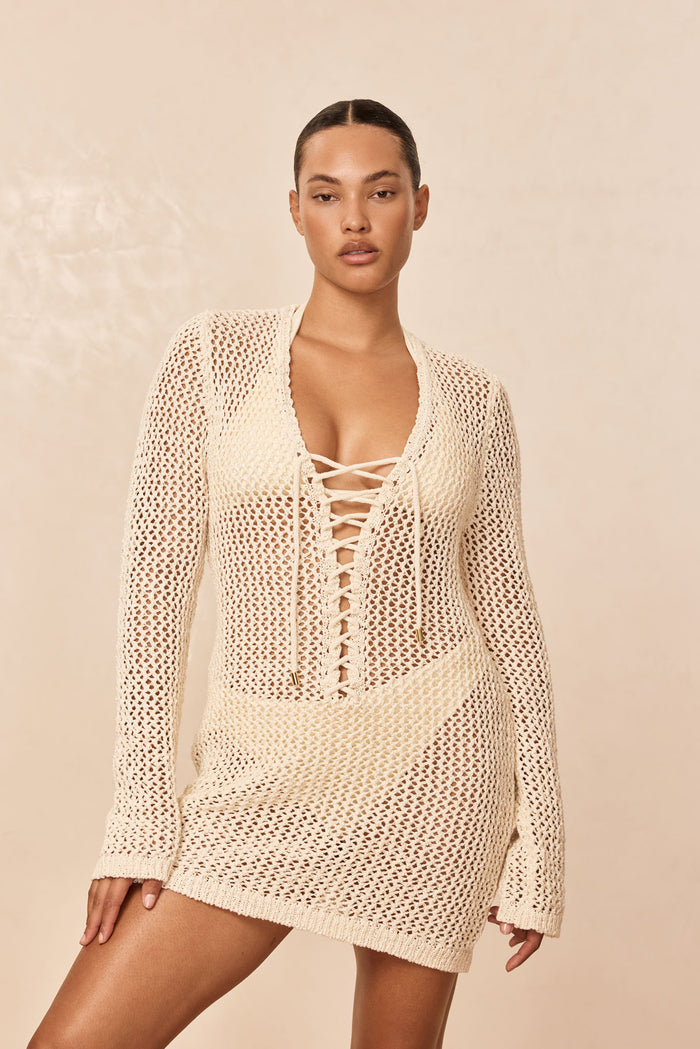 Front of Corossol Mini Dress in ivory crochet showing lace-up plunge, sleeves and sheer open-knit mini on beige background