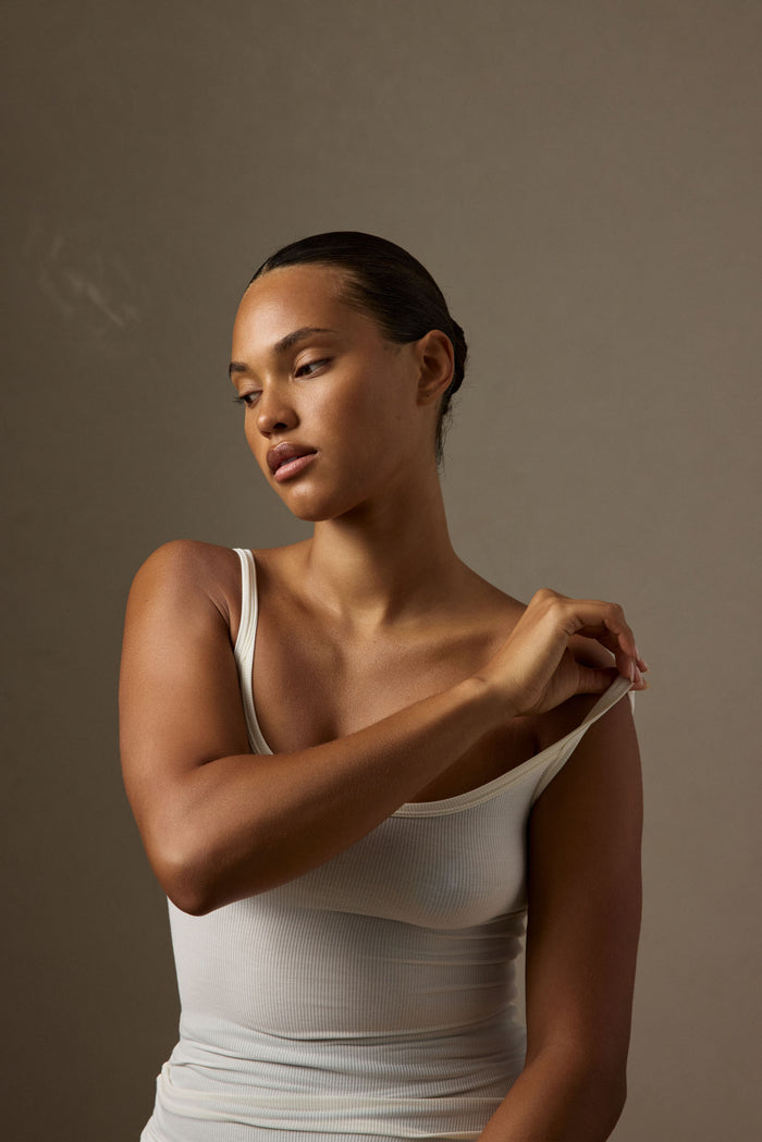 Three-quarter view of Devin Tank Long in ivory rib showing scoop neckline and ribbed texture, fitted on model