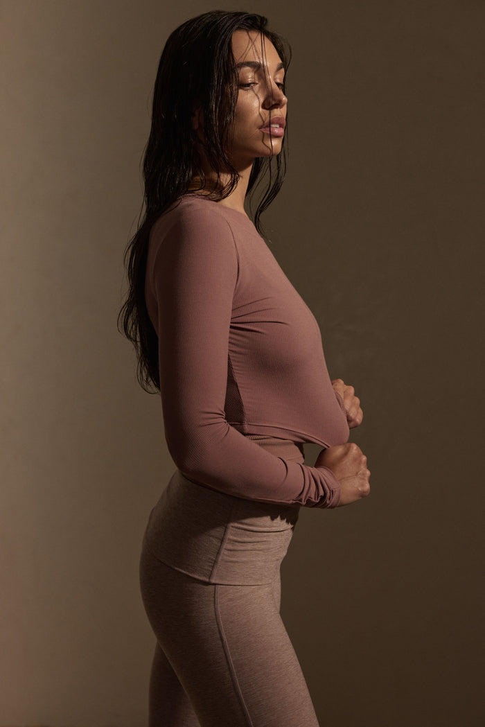 Side profile of Hayworth Long Sleeve mauve ribbed cropped top showcasing ribbed texture and fitted shape on neutral backdrop
