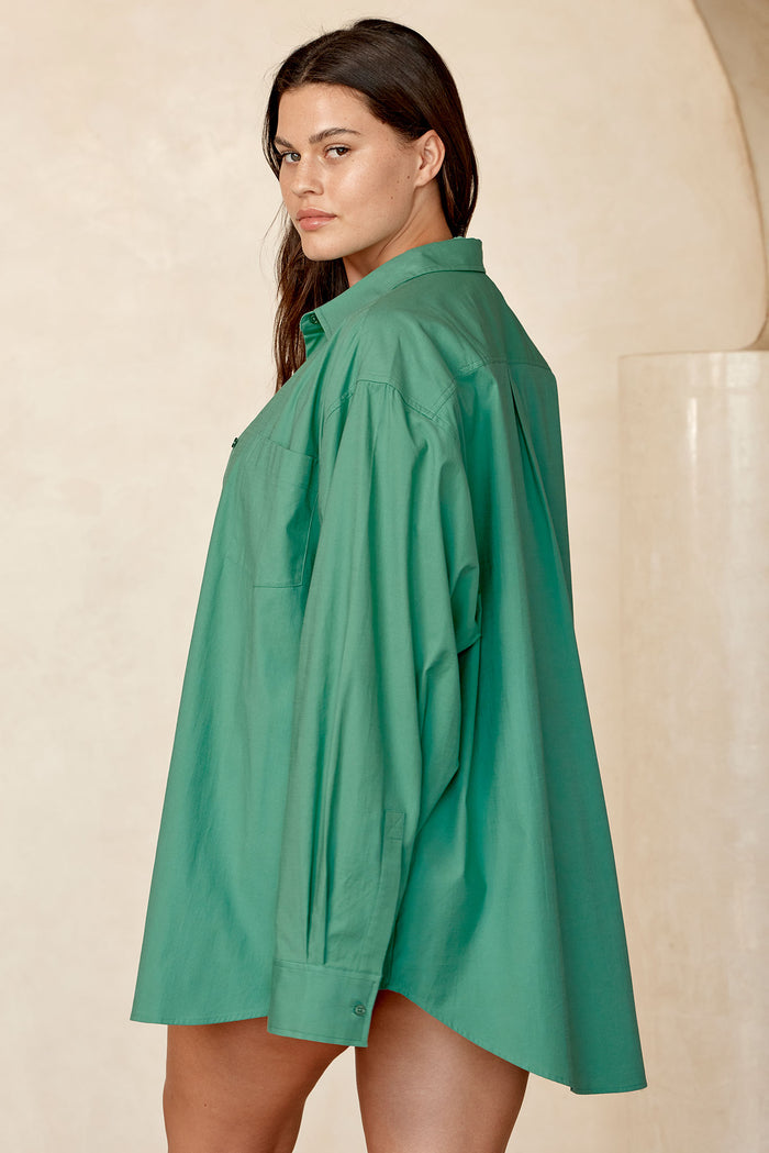Side view of La Jolla Shirt in Pond green showcasing oversized button-front fit and chest pocket with neutral beige backdrop