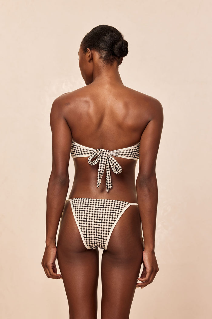 Back view of a woman wearing a black-and-white gingham strapless bikini tied at center back