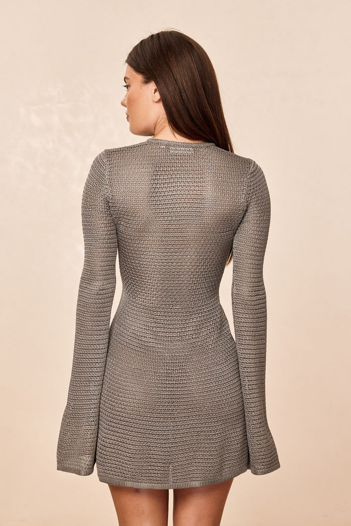 Back view of Montego Mini Dress in steel treble knit showing textured knit, long sleeves and flared skirt on beige background