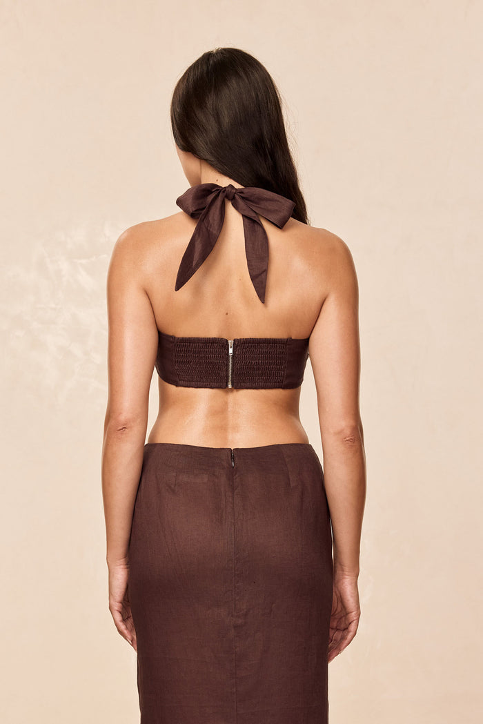 Back view of Montserrat Top in espresso linen, halter tie bow and smocked back with zipper on beige background
