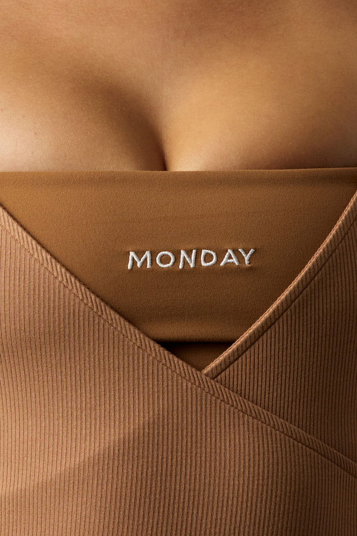 Close-up front of Olympic Tank in caramel showing ribbed crossover neckline and MONDAY embroidered shelf bra on a model