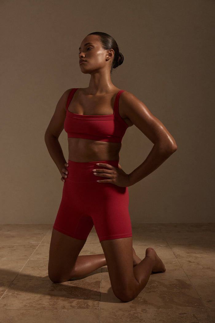 Three-quarter view of Outpost Bra - Cherry showcasing straight neckline and wide straps on model against a neutral studio background