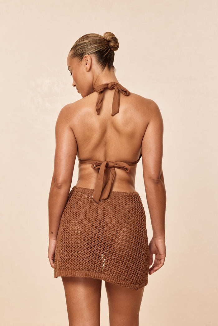 Back view of Santa Marta Sarong in Caramel Petit Crochet on model showing crochet knit, sheer fabric, and adjustable wrap-tie
