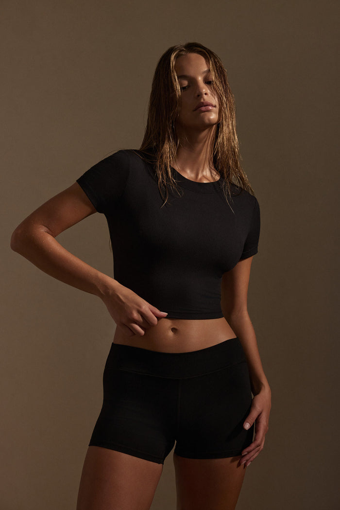 Three-quarter front view of Sedona Short in black on model showing low-rise doubled waistband and 3 3/8 inch inseam against neutral background