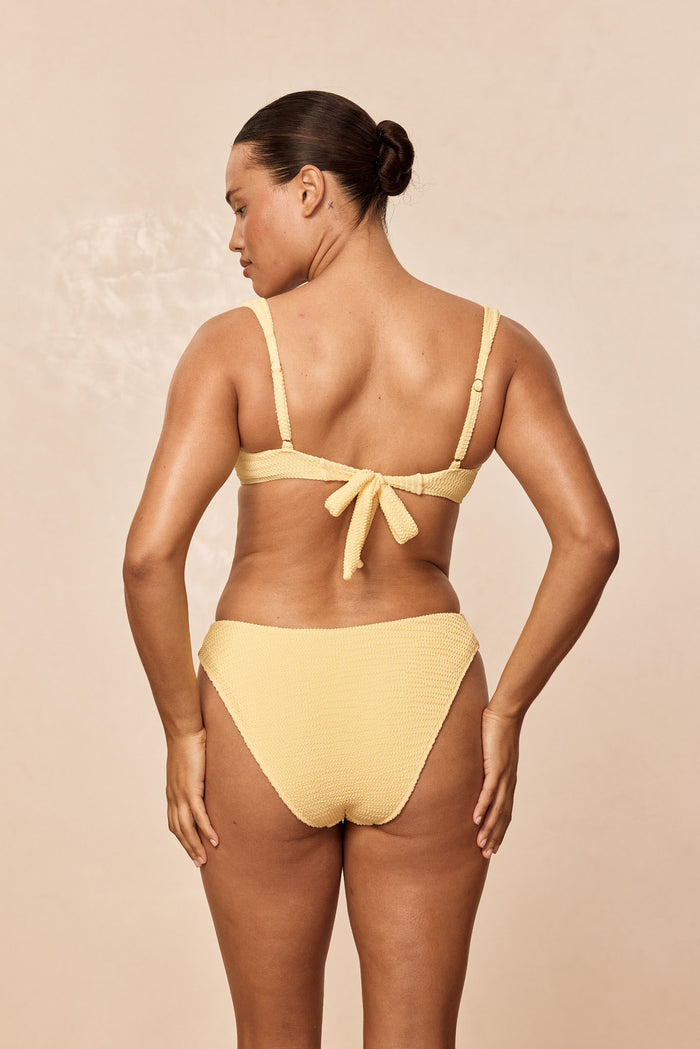 Back view of Clovelly Top in Honey Crinkle on model, showing tie-back closure and adjustable straps against beige backdrop