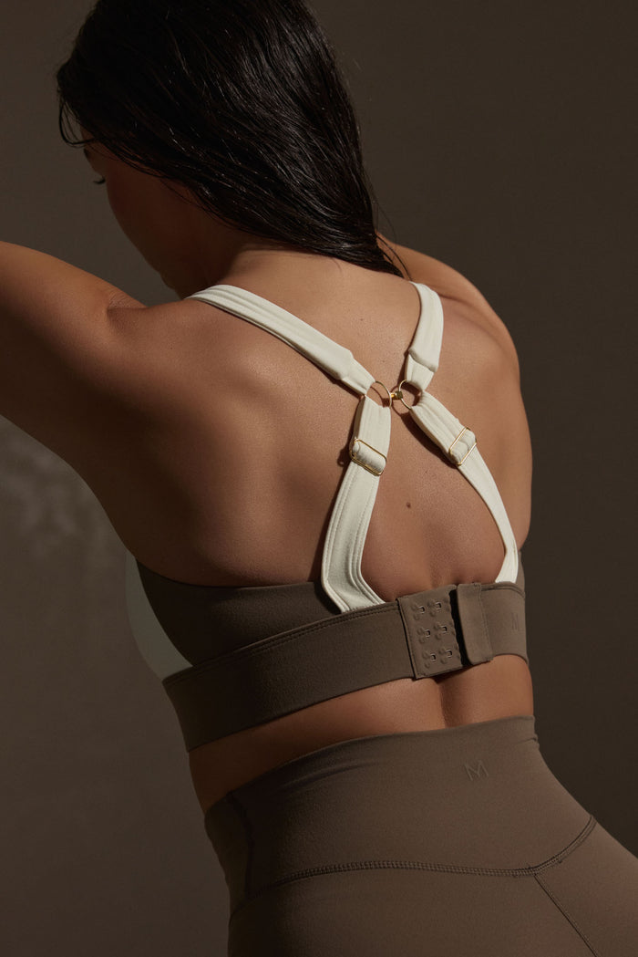 Back view of Tash Bra in stone and ivory jersey showing adjustable crossover straps with gold rings and wide hook closure