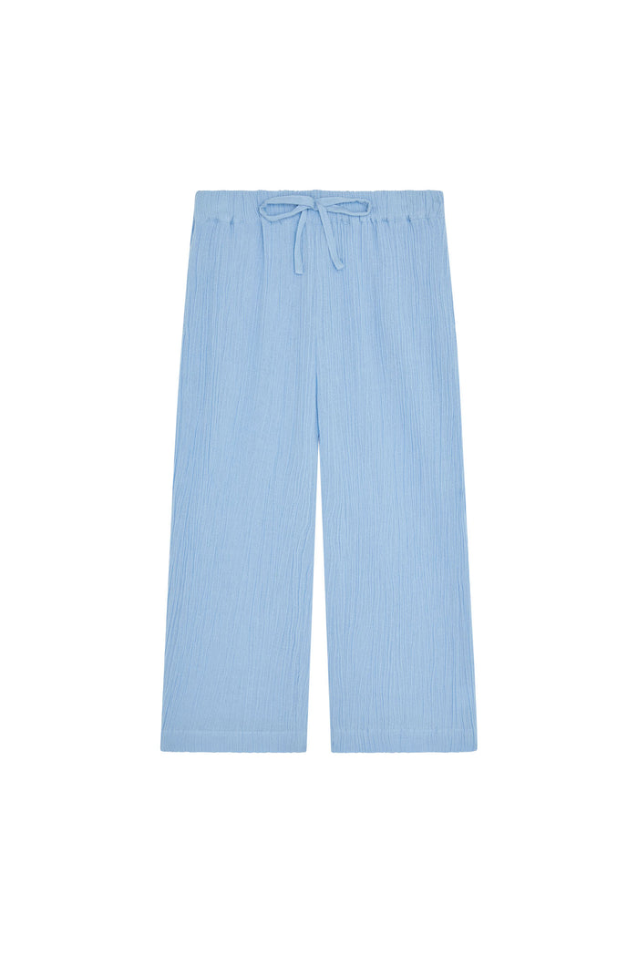 Front flat-lay of Tuscany kids pant in sky showing elastic drawstring waist, crinkled fabric texture and wide-leg silhouette on white background