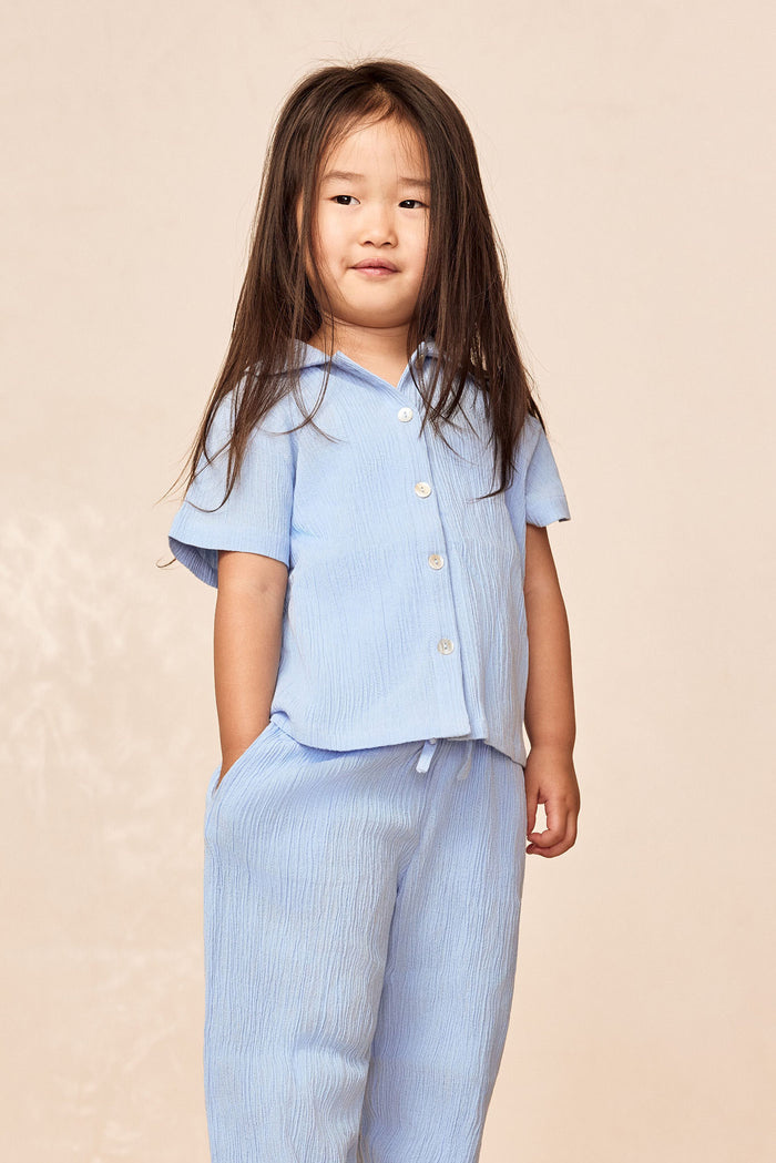 Three-quarter view of Tuscany Pants Kids in Sky with smocked waistband and relaxed wide-leg fit on child model