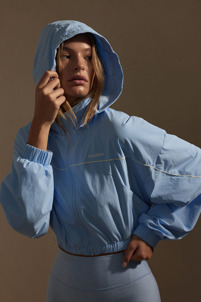 Three-quarter view of Westmount Jacket in Sky Nylon on model showing hood, cropped fit with elastic cinch hem and MONDAY logo