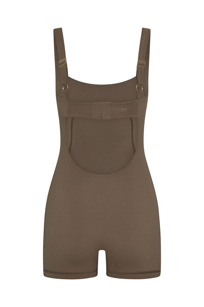 Back view of Zion Romper in stone showing open back, adjustable straps with gold hardware, and hook-and-eye back band on white background